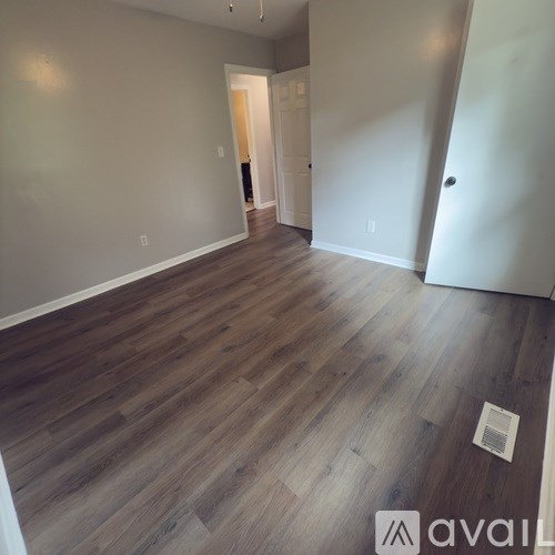 A living room with a white couch, a brown leather chair, a wooden coffee table, and a flat-screen TV mounted on the wall.