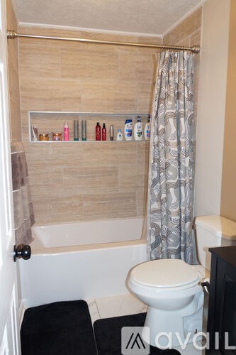 A bathroom with a toilet, a bathtub, and a shelf with bottles.