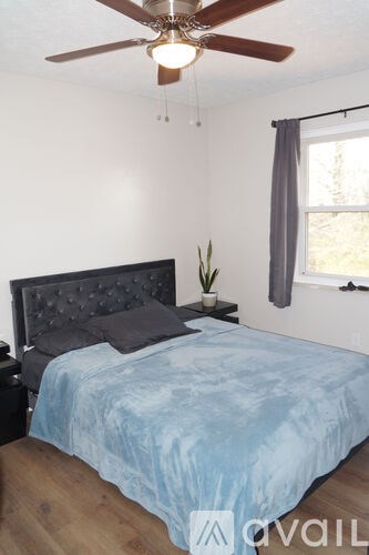 A bedroom with a bed, a ceiling fan, and a window.