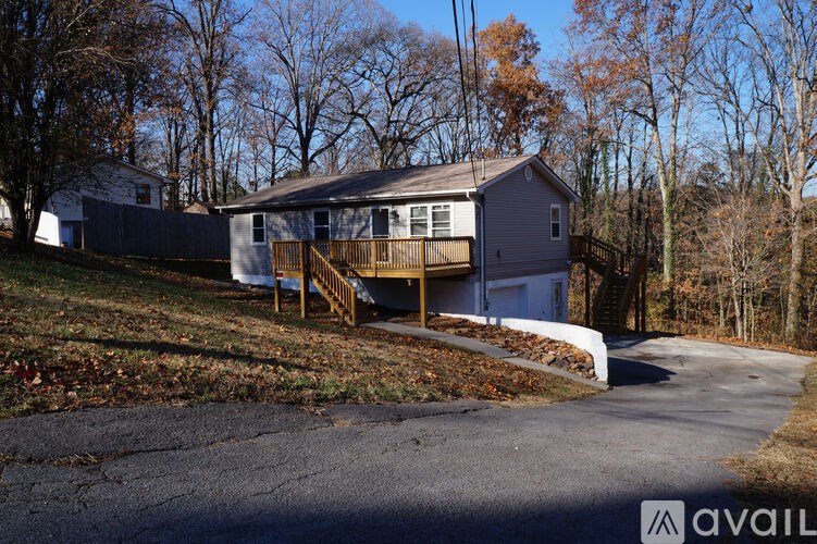 A house with a grey roof and a white garage door is surrounded by trees.