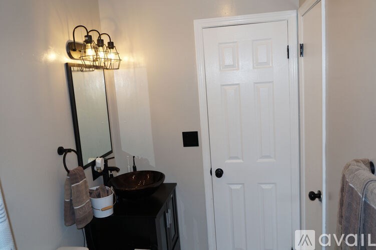 A bathroom with a white door, a mirror, and a sink.