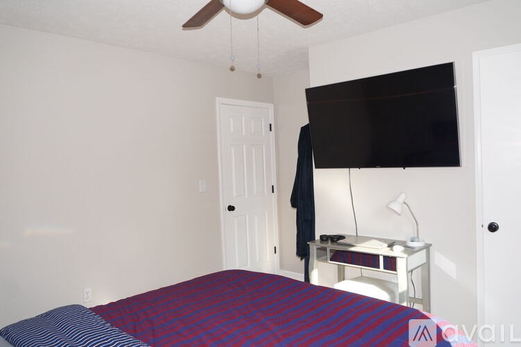 A bedroom with a bed, a television, and a ceiling fan.