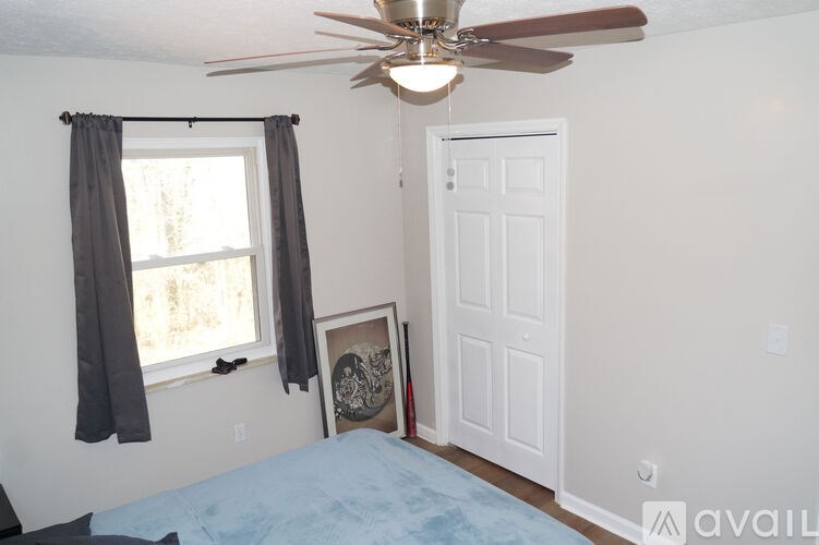 A bedroom with a bed, window, and a ceiling fan.