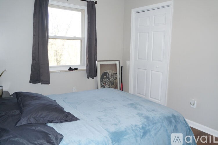 A bedroom with a bed, a window with curtains, and a white door.