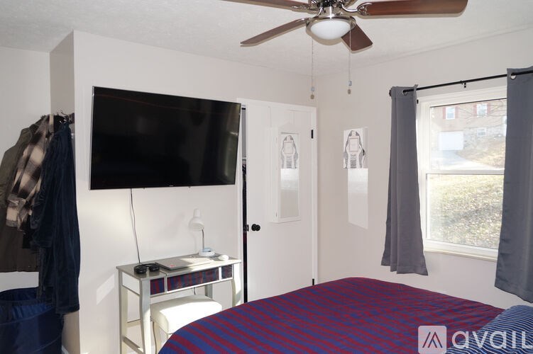 A bedroom with a bed, a television, and a window with curtains.