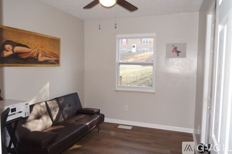 A living room with a brown couch and a painting on the wall.