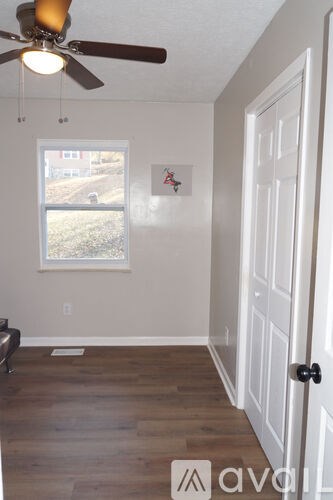 A room with a white door and a window with a view of a red building outside.