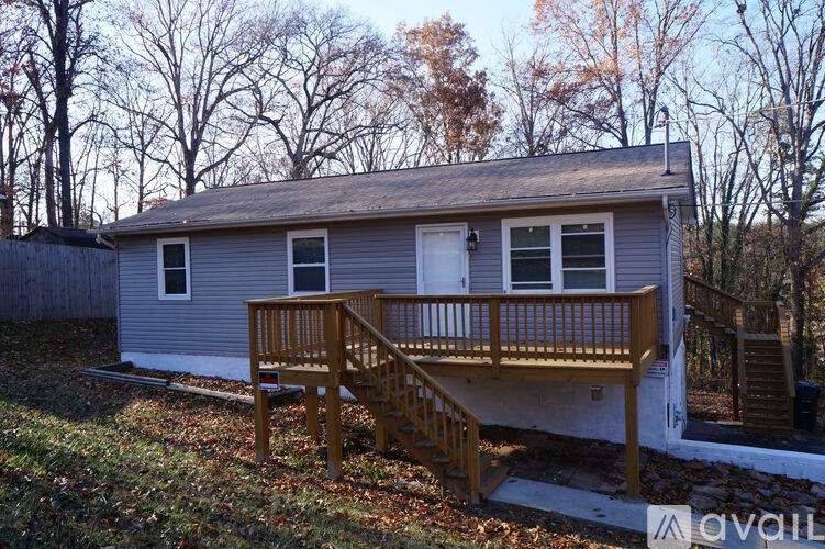A house with a grey siding and a white door is surrounded by trees.