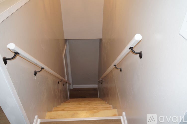 A staircase with a wooden handrail and white walls.