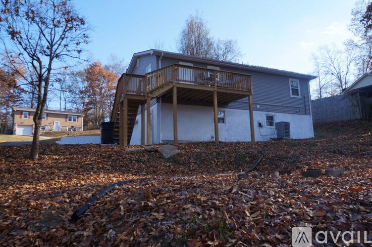 A house with a deck in the backyard surrounded by fallen leaves.
