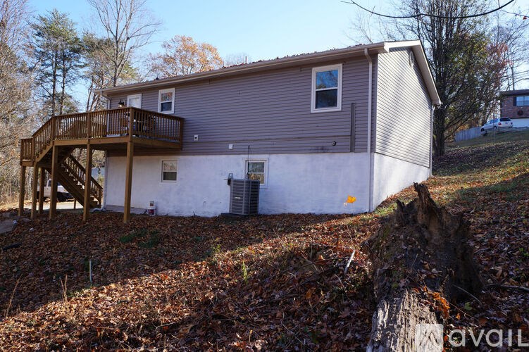 A house with a deck and a tree stump in front.