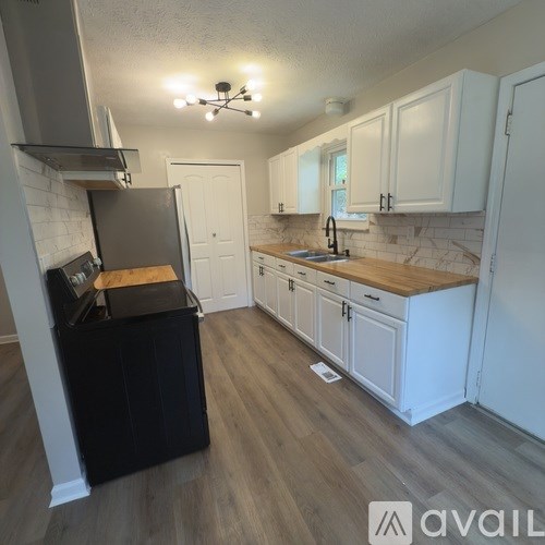 A house with a grey roof and a white window is surrounded by trees.