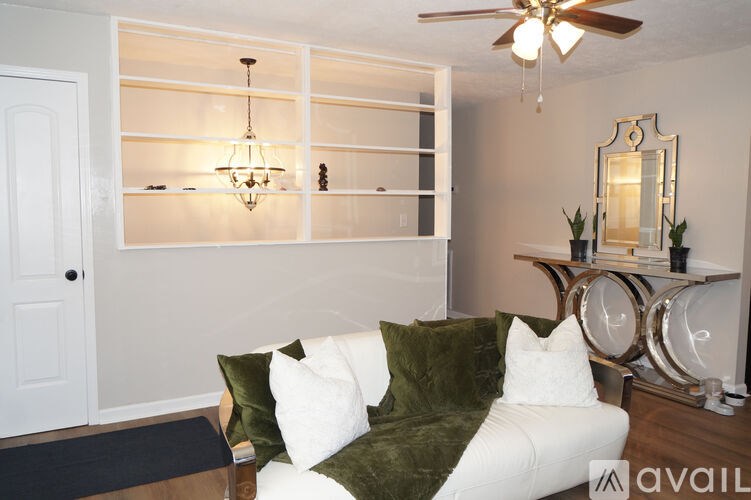 A living room with a white couch and a green pillow.
