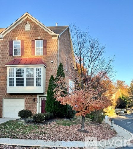 A house with a red roof and a tree with pink flowers in front.