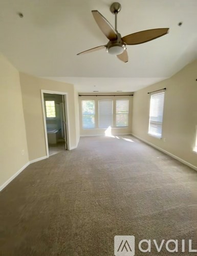 A room with a ceiling fan and carpeted floor.