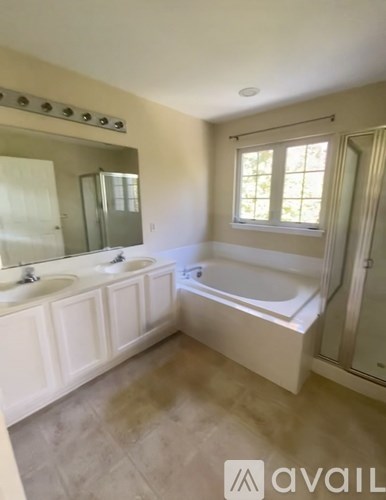 A bathroom with a tub, sink, and mirror.