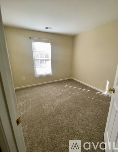 A room with a carpeted floor and a window with blinds.