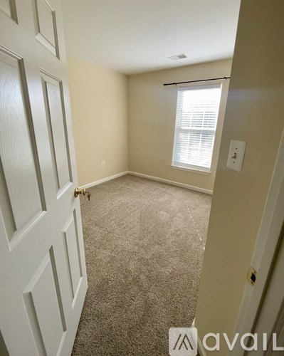 A room with a carpeted floor and a window with blinds.