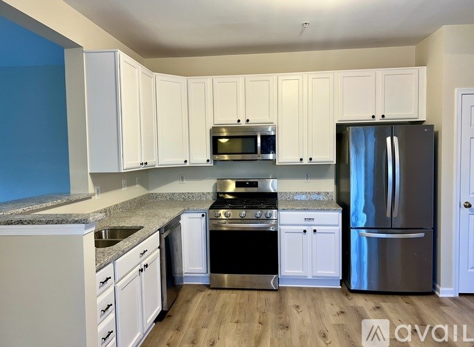 A kitchen with white cabinets and a stainless steel refrigerator.