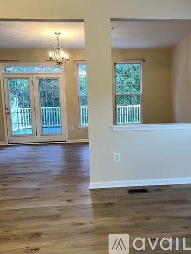 A room with a chandelier and a large window with a view of a fence and trees.