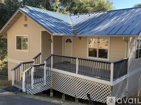 A house with a metal roof and a porch with a lattice design.
