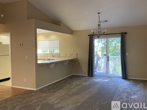 A room with a slanted ceiling, a chandelier, and a window with blinds.