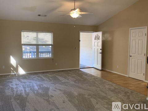 A spacious room with a rug on the floor and a ceiling fan.