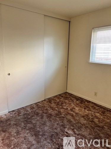A room with a carpeted floor and a window with blinds.