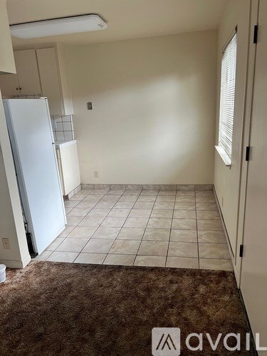 A room with a refrigerator and a brown rug.