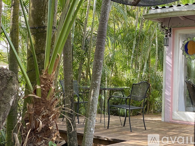 A patio with a table and chairs surrounded by trees.
