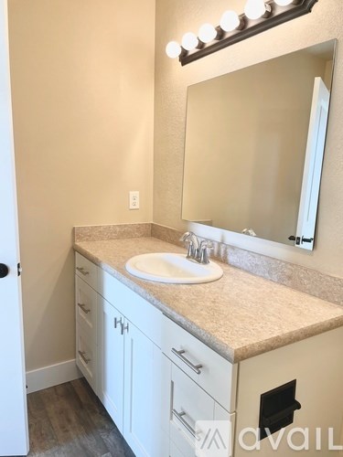 A bathroom with a sink, mirror, and lights above it.