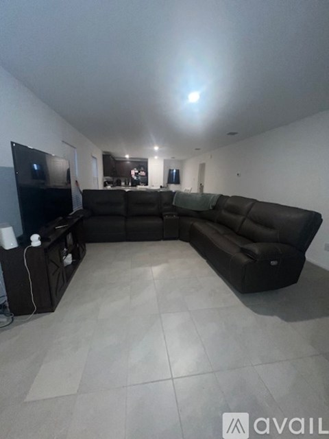 A living room with a large black leather sofa and a television.