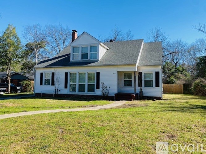 A white house with a black roof and a grey shingled area on the roof.