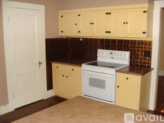 A kitchen with a white stove top oven and wooden cabinets.
