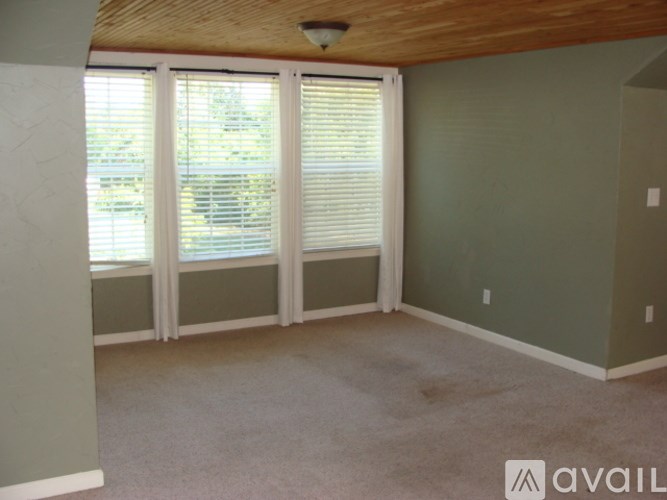 A room with a window covered by white blinds.