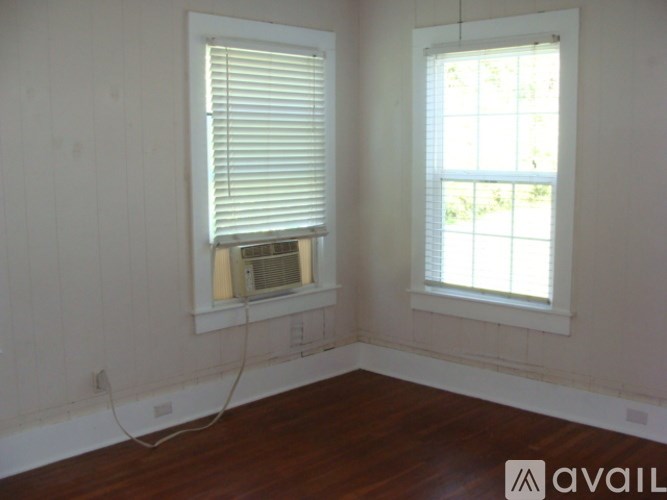 A room with two windows and wooden floors.