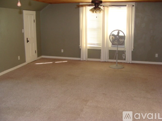 A room with a fan and a window with blinds.