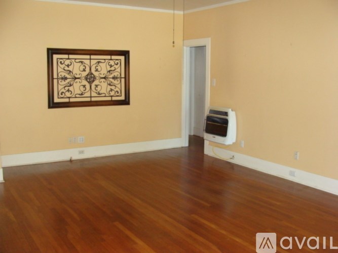A room with wooden floors and a framed picture on the wall.