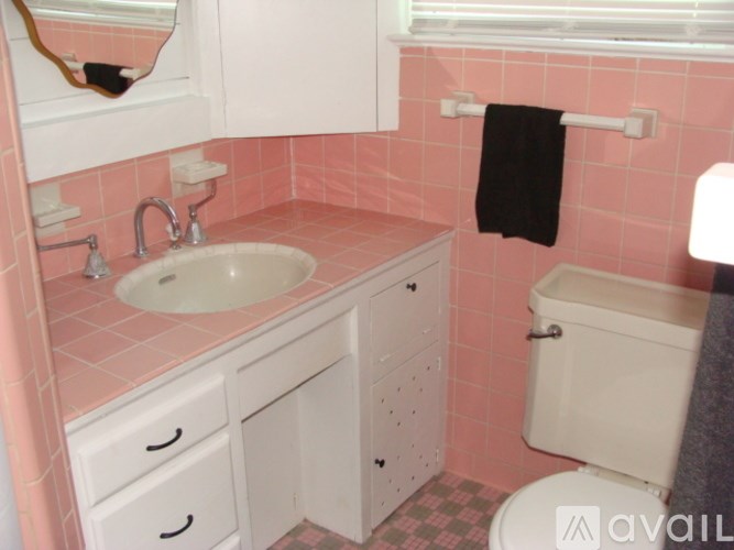 A bathroom with pink tiles and white fixtures.