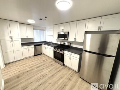 A kitchen with white cabinets and a wooden floor.