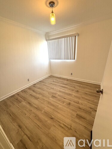 A room with wooden flooring and a light hanging from the ceiling.