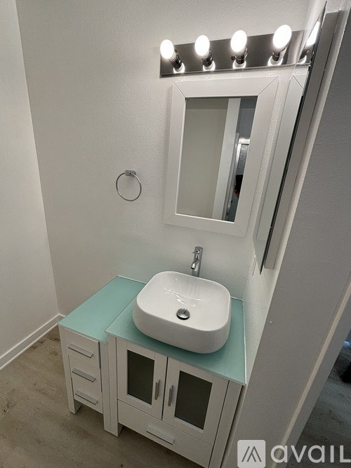 A bathroom with a sink and a mirror with lights on it.