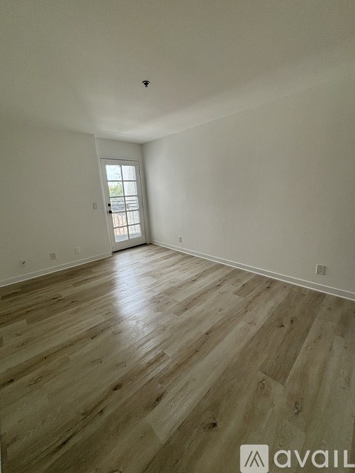 A room with wooden flooring and a door leading outside.