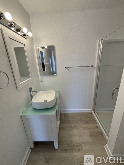 A bathroom with a sink, mirror, and lighting fixtures.