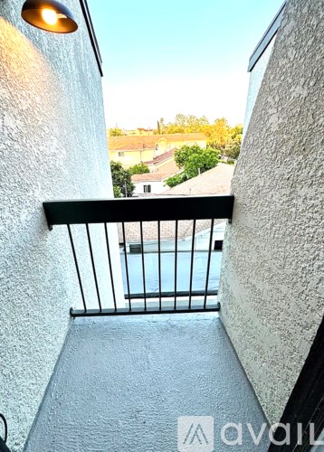 A balcony with a metal railing and a view of a pool and houses.