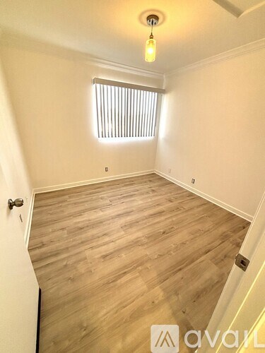 A room with wooden flooring and a window with blinds.