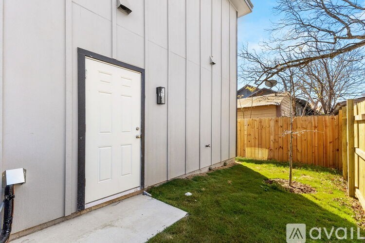 A white door is on the left side of a grey building.