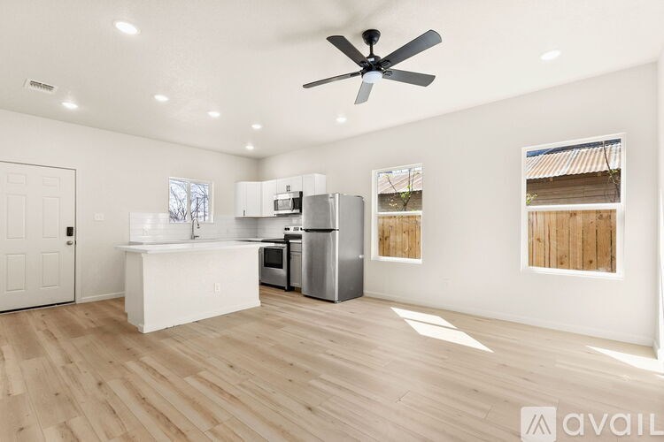 A spacious kitchen with a refrigerator, sink, and a ceiling fan.