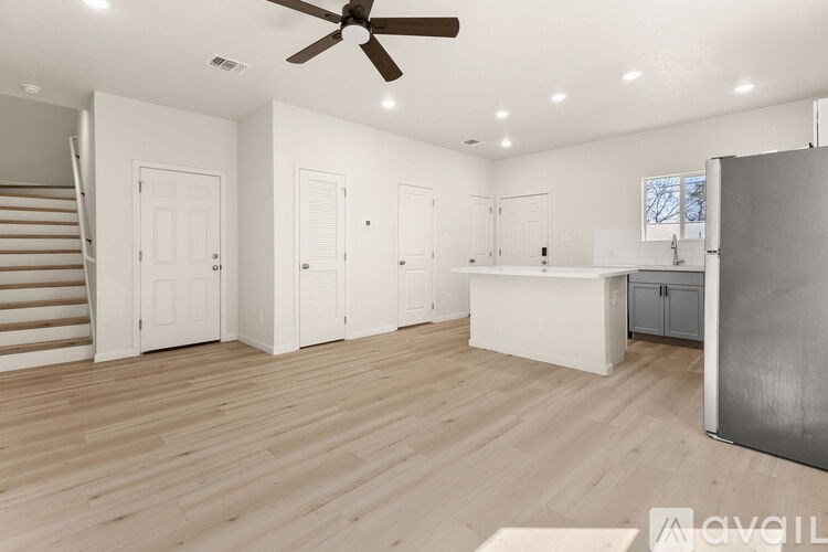 A spacious room with wooden floors and a ceiling fan.