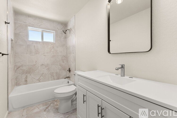 A bathroom with a white tub, sink, and tiled walls.